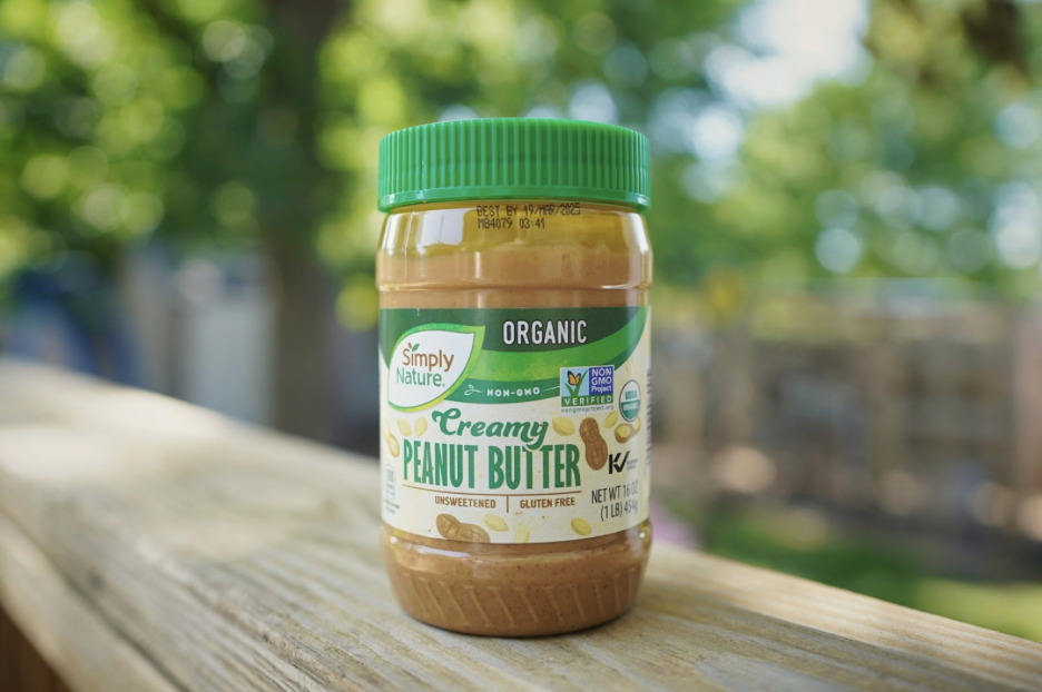 A plastic jar of peanut butter sits on a wooden surface.